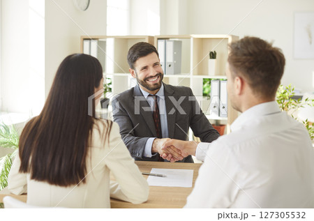 Husband And Wife Shaking Hands With Consultant In Office Husband And Wife Shaking Hands With Consultant In Office 127305532