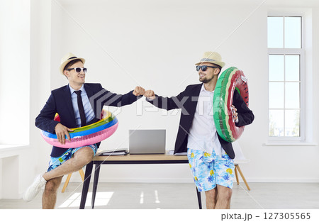Company employees in sunglasses and beach hats standing in office ready for summer vacation. 127305565