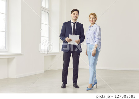 Realtor and young woman standing in light empty new apartment, agent helping clients buy, rent home 127305593
