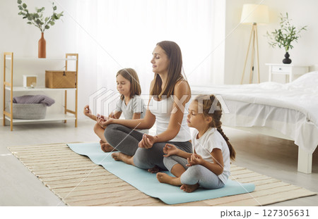 Family yoga, peaceful calm mother, kids, mum practicing yoga exercises with small children at home 127305631