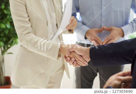 Close up of handshake between woman in beige suit and man, making business deal, reaching agreement. 127305690