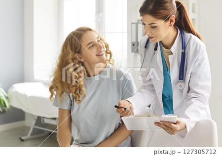 Young woman patient talking with doctor sitting in office during medical examination in clinic Young woman patient talking with doctor sitting in office during medical examination in clinic 127305712