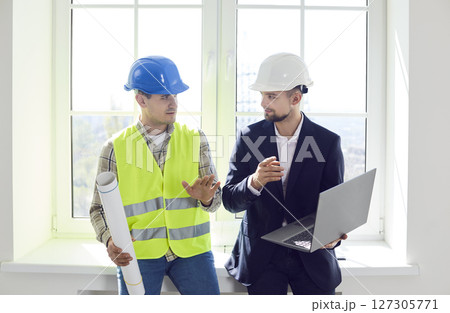Young foreman discussing with architect design project or repair of new apartment on laptop 127305771