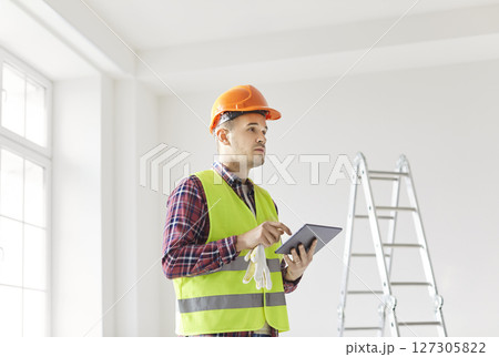 Worker Planning Renovation Using Tablet Pc And Blueprint At Home Worker Planning Renovation Using Tablet Pc And Blueprint At Home 127305822