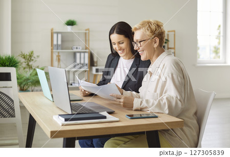 Coworkers Collaborating On Laptop And Documents During Meeting Coworkers Collaborating On Laptop And Documents During Meeting 127305839