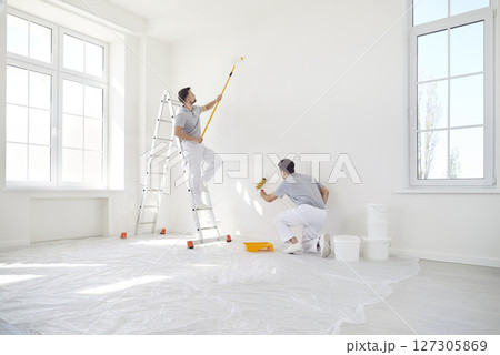 Team Of Male Painters Painting Wall During Home Or Office Renovation Team Of Male Painters Painting Wall During Home Or Office Renovation 127305869