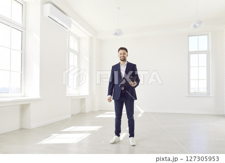 Happy realtor standing in empty white room, flat, house, cottage for sale, real estate purchase Happy realtor standing in empty white room, flat, house, cottage for sale, real estate purchase 127305953