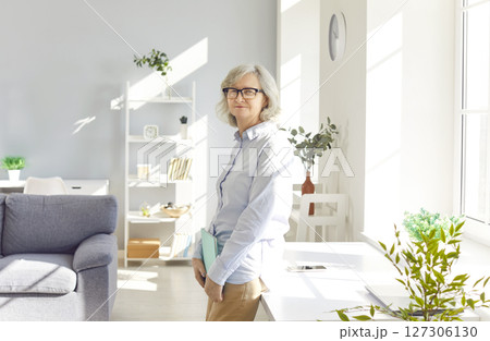 Portrait of confident smiling senior woman standing at home and looking cheerful at camera Portrait of confident smiling senior woman standing at home and looking cheerful at camera 127306130