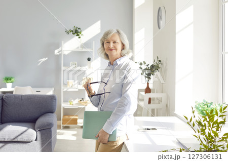 Portrait of confident smiling senior woman standing at home and looking cheerful at camera Portrait of confident smiling senior woman standing at home and looking cheerful at camera 127306131