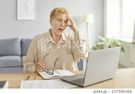 Mature tired unhappy freelance business woman in glasses sad working at home, laptop, typing Mature tired unhappy freelance business woman in glasses sad working at home, laptop, typing 127306168