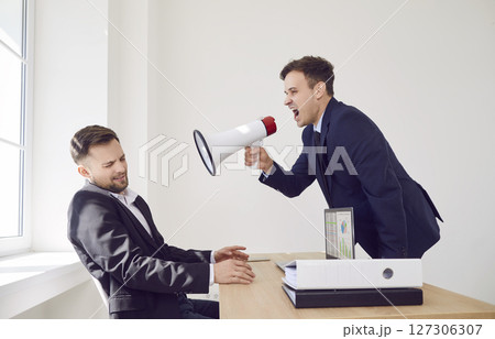 Angry boss with megaphone shouts at man in office, close-up Angry boss with megaphone shouts at man in office, close-up 127306307