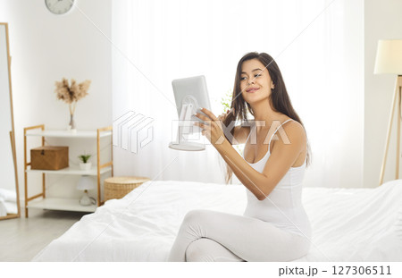 Morning home care, beautiful female looking in mirror doing beauty procedures, combing hair 127306511