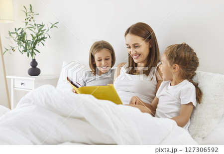Mother Reading A Book With Children In Bed During Leisure Time At Home Mother Reading A Book With Children In Bed During Leisure Time At Home 127306592