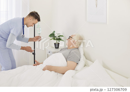 Doctor Or Nurse Setting Up An Iv Drip For A Senior Man At Hospital 127306709