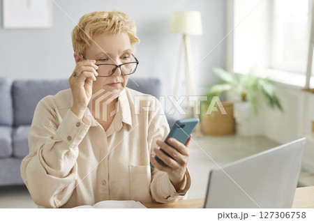 Serious focused woman, pensive lady using mobile phone for work at desk, communication, thinking Serious focused woman, pensive lady using mobile phone for work at desk, communication, thinking 127306758