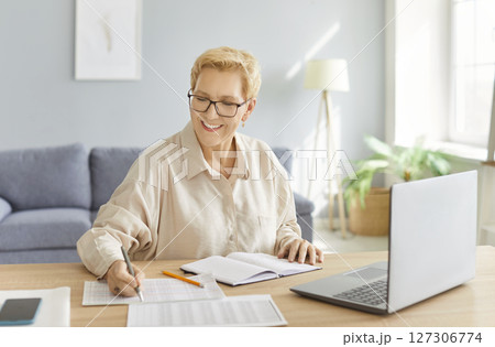Senior accountant woman sitting on workplace at the desk with laptop working with charts 127306774