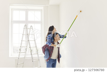 Family Couple Painting Walls Together In New Home Renovation 127306780