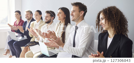 Young business people in formal clothes applauding to speaker sitting in a row in meeting room Young business people in formal clothes applauding to speaker sitting in a row in meeting room 127306843