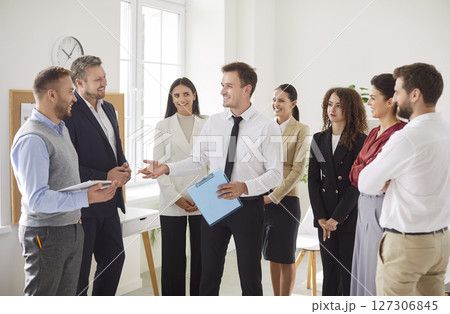 Group of business people chatting on a meeting standing in circle in office discussing work project. Group of business people chatting on a meeting standing in circle in office discussing work project. 127306845