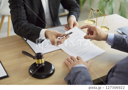 Man signing a contact with male advocate sitting on workplace in office 127306922