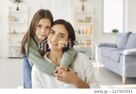 Portrait of smiling happy young mother with teen daughter looking at camera at home. Portrait of smiling happy young mother with teen daughter looking at camera at home. 127307041