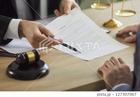 Legal advisor helping client to sign contract, giving consultation in his cabinet Legal advisor helping client to sign contract, giving consultation in his cabinet 127307067