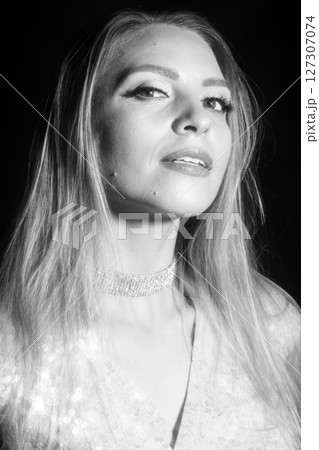 Beautiful blonde woman with shiny blouse black and white studio portrait 127307074