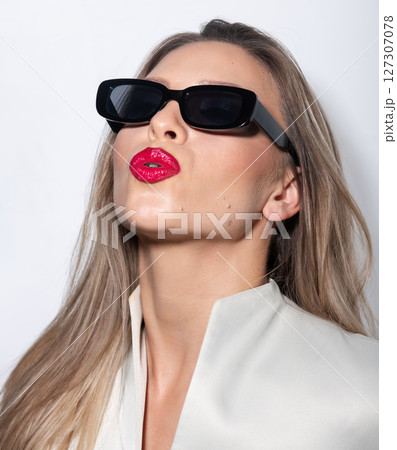 Beautiful woman close-up studio portrait with white sunglasses and red lipstick sending kiss Beautiful woman close-up studio portrait with white sunglasses and red lipstick sending kiss 127307078