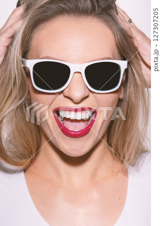 Beautiful woman close-up studio portrait with white sunglasses and red lipstick 127307205