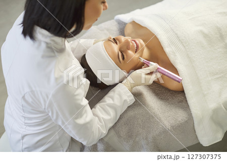 Cosmetologist, dermatologist beautician using dermapen miconeedling roller pen performing face care 127307375