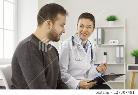 Friendly doctor and patient discuss treatment plan during medical examination in clinic. 127307481