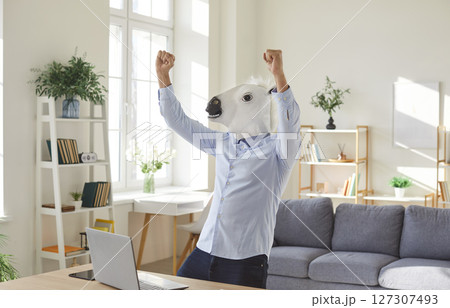 Business man wearing horse animal mask in the office raising his hands up in fists like a winner. 127307493