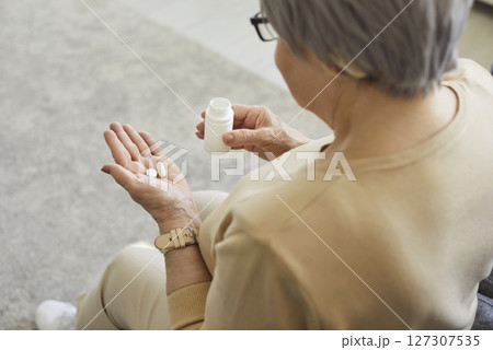 Back view of middle aged woman holding bottle of drugs, taking medicine prescribed by doctor Back view of middle aged woman holding bottle of drugs, taking medicine prescribed by doctor 127307535