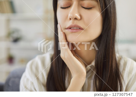 Closeup portrait of a young upset woman suffering from toothache at home. 127307547
