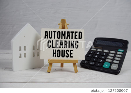 ACH Automated Clearing House text on paper card with white house model and calculator on wooden background ACH Automated Clearing House text on paper card with white house model and calculator on wooden background 127308007