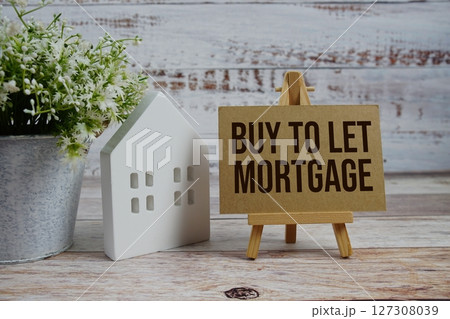 Buy To Let Mortgage on paper card with white house model on wooden background 127308039
