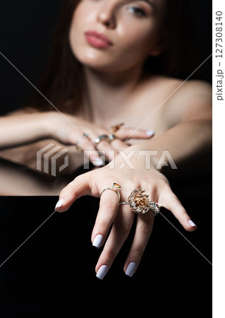 Studio portrait of beautiful and sexy brunette woman with fancy make-up and various rings on her fingers 127308140