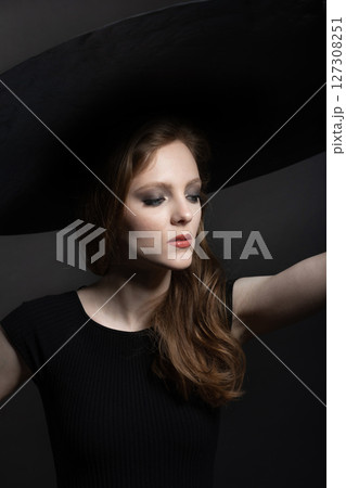 Woman with big black hat studio portrait Woman with big black hat studio portrait 127308251