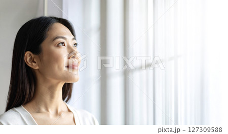 斜め上を見上げて微笑む中年女性と明るいコピースペース　AI生成画像 127309588