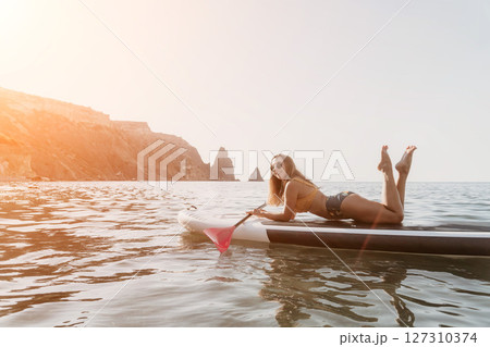 Woman Paddleboard Ocean Relaxing on a Paddleboard in the Ocean near Rocky Cliffs. 127310374