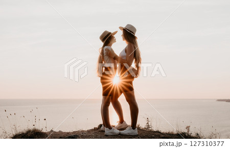 Two Women Embracing at Sunset on a Cliff Two Women Embracing at Sunset on a Cliff 127310377