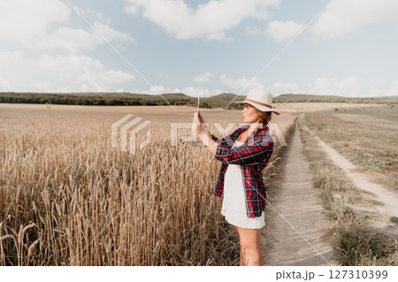 Young Woman in a Field Taking a Picture with a Tablet Young Woman in a Field Taking a Picture with a Tablet 127310399