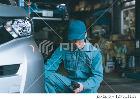 タイヤ空気圧点検をする自動車整備士 127311115