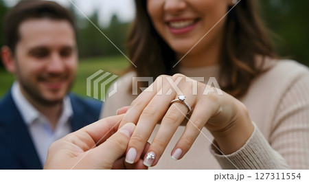 Woman showing engagement ring with smiling partner in outdoor proposal moment Woman showing engagement ring with smiling partner in outdoor proposal moment 127311554
