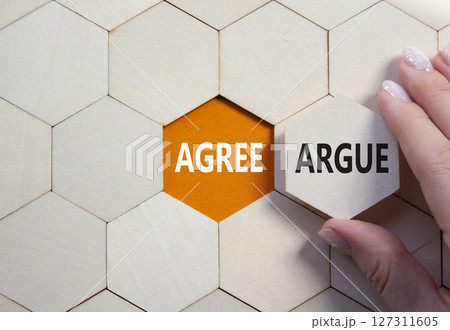 Agree or Argue symbol. Concept word Agree or Argue on wooden comb puzzle. Businessman hand. Beautiful orange background. Business and Agree or Argue concept. Copy space 127311605
