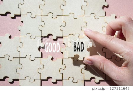 Good or Bad symbol. Concept word Good or Bad on wooden puzzle. Businessman hand. Beautiful pink background. Business and Good or Bad concept. Copy space Good or Bad symbol. Concept word Good or Bad on wooden puzzle. Businessman hand. Beautiful pink background. Business and Good or Bad concept. Copy space 127311645