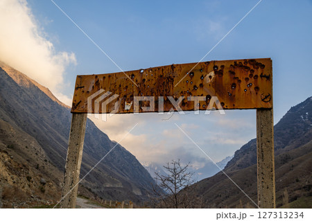 Bullet-ridden rusty sign in desolate mountainous region of Kyrgyzstan 127313234
