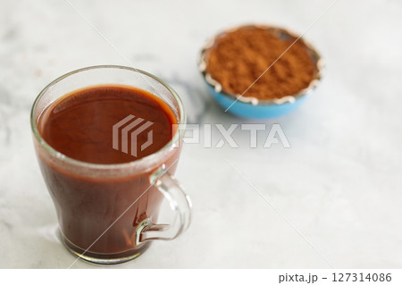 Hot Chocolate in Transparent Cup with Bowl of Cocoa Powder on Gray Concrete, Copy Space Hot Chocolate in Transparent Cup with Bowl of Cocoa Powder on Gray Concrete, Copy Space 127314086