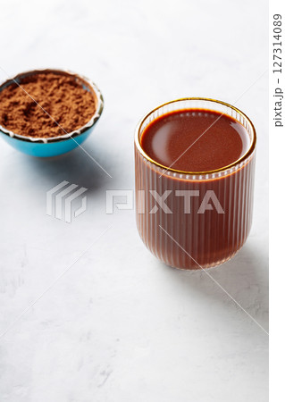Cocoa Drink in Ridged Glass with Gold Rim and Bowl of Cocoa Powder on Concrete Background, Copy Space Cocoa Drink in Ridged Glass with Gold Rim and Bowl of Cocoa Powder on Concrete Background, Copy Space 127314089