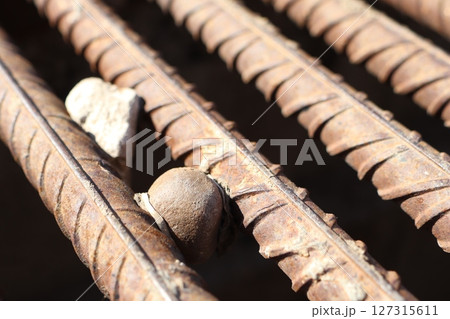 A closeup view capturing the intricate details of rusted rebar intermingled with stones 127315611